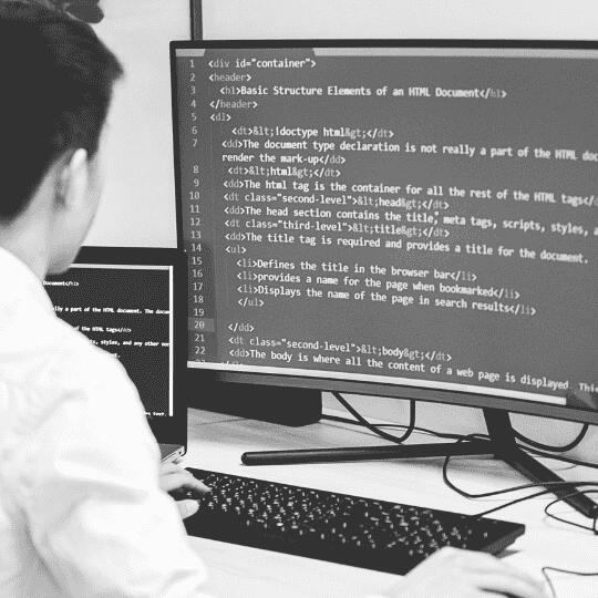 Black and white image of a guy coding on a laptop, illustrating the process of building a business website with CodexCon.